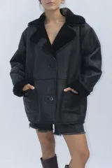 Campera de cuero genuino color negro con interior y detalles en piel sintética negra. Presenta un diseño de corte holgado, cuello solapa, cierre frontal con botones y bolsillos delanteros.