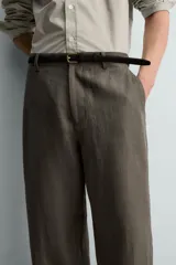 Pantalón straight fit color verde militar, confeccionado en lino, con cintura con trabillas, cierre frontal con cremallera y botón, y bolsillos laterales.