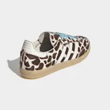 Championes Adidas Samba OG con diseño de estampado animal print tipo jirafa en tonos marrón y blanco. Presenta las icónicas tres bandas laterales en color blanco, cordones en celeste y suela de goma color caramelo.