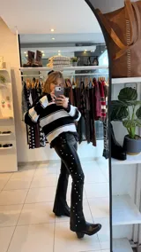 Pantalon de gabardina elastizada color negro, de corte ajustado con diseño de tachas metálicas plateadas a lo largo de las costuras laterales.