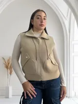 Chaleco beige con cierre frontal y bolsillos grandes.