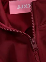 Campera deportiva de cuello alto y cierre frontal completo, confeccionada en tejido interlock color bordó. Presenta mangas largas con franjas laterales decorativas y puños elásticos.