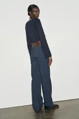 Camiseta de cuello barco y manga larga con diseño asimétrico en el bajo. Presenta un corte entallado con cierre lateral mediante cremallera oculta.