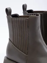 Bota tipo Chelsea de símil cuero color suela, con plataforma oscura, punta cuadrada y paneles elásticos laterales.