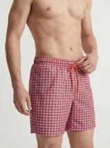 Short de baño rojo con estampado geométrico, cintura elástica con cordón de ajuste naranja y bolsillos delanteros.