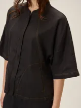 Chaqueta Marion de lino y rayón color negro, con cuello mao, mangas cortas amplias y pespuntes a contratono en color ocre que destacan el diseño.