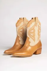 Bota texana de cuero color marrón claro con detalles en beige. Diseño con puntera en punta y caña media con bordados decorativos. Taco bajo de madera.