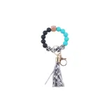 Llavero pulsera con cuentas de silicona negras, celestes y animal print, con dije de flecos de cuero sintético con estampado animal print y gancho metálico dorado.