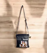Bandolera negra de cuero con solapa frontal decorada con una intervención artística pintada a mano y correa larga ajustable para llevar al hombro o cruzada.