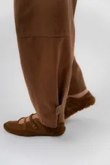Pantalón de gabardina de algodón color negro, con calce barrel, cintura media baja, recortes de diseño y detalle de botones en el ruedo para ajustar el volumen.