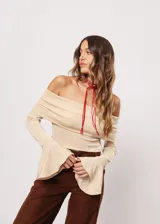 Blusa beige con hombros descubiertos, mangas largas acampanadas y confeccionada en tela stretch con lurex.