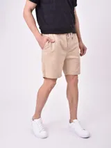 Bermuda de gabardina color kaki, con cintura elástica y cordón de ajuste, bolsillos laterales y corte recto.