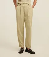 Pantalón zanahoria de cintura alta color beige, confeccionado en tejido piqué con viscosa sostenible. Cuenta con cierre tradicional, cintas con botones en la cintura, pliegues y dobladillo en el bajo.