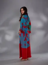 Kimono largo de algodón texturado con estampado vegetal en tonos rojo, azul y verde. Cuenta con mangas amplias, cinto independiente para ajustar a la cintura, bolsillos laterales y aberturas laterales en el dobladillo con detalles de flecos.