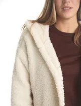 Cardigan de textura tipo corderito, color blanco, con diseño abierto sin botones, capucha amplia y mangas largas con puños de rib elástico. Cuenta con bolsillos delanteros de corte diagonal.