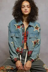 Campera de jean con textura acanalada, cierre frontal y diseño con apliques de estrellas desgastadas. Presenta detalles de tela escocesa en los puños y el ruedo, con bordes desflecados y bolsillos frontales con solapa.