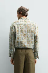 Camisa de corte relajado confeccionada en tejido fluido con estampado geométrico en tonos azules y ocres. Presenta cuello solapa, cierre frontal de botones y manga larga con puños abotonados.