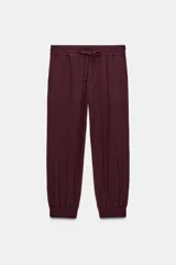 Pantalón jogger de tiro medio, color bordó, con cintura elástica ajustable mediante cordones, bolsillos delanteros y puños elásticos en los tobillos.