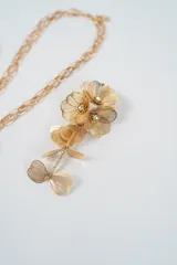 Set de joyería compuesto por un collar de cadena larga con dije floral y un par de aros colgantes a juego. Ambas piezas presentan un diseño de flores caladas en metal dorado con detalles de cristales en el centro.