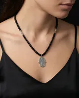 Collar de acero con cuentas de cristal negro y dije central en forma de mano de Hamsa con detalles grabados.
