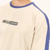 Remera de algodón color beige con cuello redondo y detalles de franjas laterales en color azul. Presenta un estampado frontal con el logo de la marca en el centro del pecho.