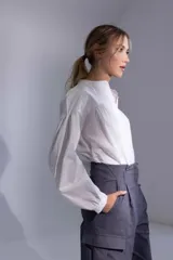 Camisa blanca de poplin 100% algodón, con cuello mao y recortes en delantero pespunteados con frunces. Las mangas largas tienen detalle de frunce tanto en la copa como en sus puños. En la espalda un canesú con detalle de pespunte y en el centro frunces.