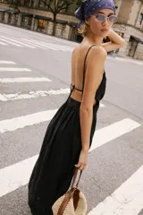 Vestido midi negro de escote recto con tirantes finos ajustables, espalda descubierta y falda amplia con bajo de bordados perforados a tono y detalle de puntilla.