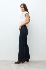 Pantalón de jean oscuro de tiro alto, corte recto y pierna ancha, con costuras verticales marcadas en el frente.
