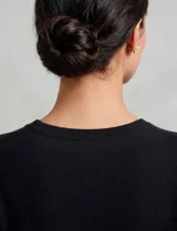 Buzo de tejido fino en color negro, con escote en V decorado con perlas y strass bordados. Presenta mangas largas con puños en punto rib y ruedo con terminación acanalada.