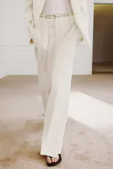 Pantalón de tiro medio de ZARA Woman Collection confeccionado en hilatura de viscosa. Cuenta con cintura con trabillas, bolsillos laterales, raya planchada y pierna recta con bajo asimétrico y aberturas. Cierre frontal con cremallera, botón y ganchos metálicos.
