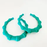 Par de aros tipo argolla de resina color lila, con diseño que imita cañas de bambú.