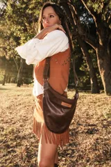 Bandolera de cuero 100% natural, color marrón oscuro, con diseño minimalista y acabado artesanal. Tiene una correa ajustable y un parche con el logo de la marca.