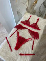 Conjunto de lencería de tres piezas en encaje rojo, compuesto por un bralette triangular, una tanga regulable y un portaligas con volados en las caderas.