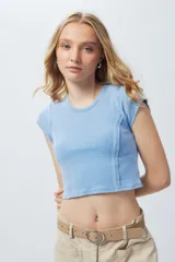 Top corto de manga corta, color negro con efecto desgastado o acid wash, cuello redondo y costuras verticales que definen la silueta.