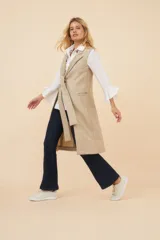 Chaleco largo color marrón claro, abierto, con lazo en la delantera y bolsillos ojal. Confeccionado en lana fina sin teñir.