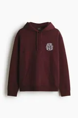 Canguro de corte holgado en mezcla de algodón, con interior suave, capucha con cordón ajustable, hombros caídos y bolsillo frontal tipo canguro. Presenta un estampado gráfico circular en el pecho y acabados acanalados en puños y bajo.