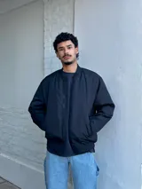 Campera bomber negra de nylon con cierre frontal y bolsillos laterales.