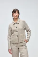 Campera corta de lana con cuerpo de tejido compacto y mangas de punto acanalado. Presenta cuello camisero, cierre frontal con botones oscuros y dos bolsillos frontales tipo plaque.