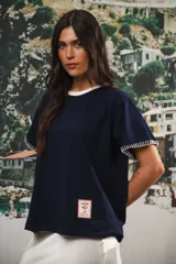 Remera de algodón color azul marino, corte relajado con hombro caído. Presenta cuello redondo blanco y bordado a mano en contraste en los puños de las mangas. Tiene un parche bordado en la parte inferior del frente.