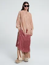 Vestido largo de terciopelo color rosa degradado, con mangas largas abullonadas y cuello redondo con lazo.