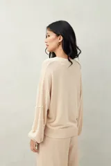 Sweater de punto color beige claro, con cuello redondo y manga larga, decorado con perlas aplicadas en patrón de rombos.