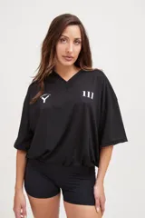 Camiseta negra de manga corta con cuello en V, corte holgado y cordón ajustable en la cintura.