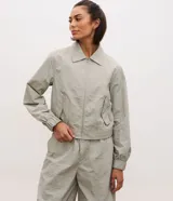Campera deportiva de corte oversized, confeccionada en poliamida con tecnología dry. Presenta cuello camisero estructurado, cierre frontal con cremallera, bolsillos laterales, puños elásticos y ruedo con ajuste elástico.
