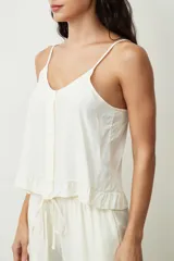 Musculosa color crudo con escote en V y botones frontales. Presenta un pequeño volante en el ruedo inferior.