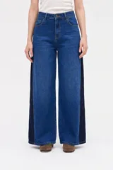 Jean de corte wide leg con diseño bicolor, combinando un tono de denim azul medio en el frente y un tono azul oscuro en los laterales. Presenta cintura alta, cierre frontal con botón y bolsillos laterales.