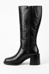 Bota de caña alta confeccionada en cuero color negro, con diseño clásico de punta cuadrada y taco ancho.