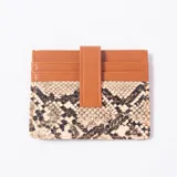 Tarjetero con diseño combinado de cuerina lisa color suela y parte inferior con estampado animal print tipo serpiente. Cuenta con ranuras para tarjetas y una tira vertical con broche para asegurar.