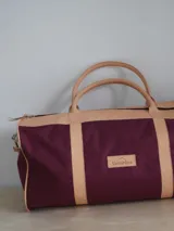 Bolso de lona color verde militar con detalles en cuero marrón. Tiene doble asa de mano y correa de hombro ajustable y extraíble.