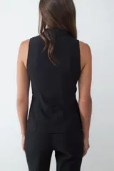 Pantalón negro de tiro medio con corte flare, confeccionado en tejido elasticado. Presenta una costura central y una pequeña abertura en el ruedo. Cierre frontal oculto.