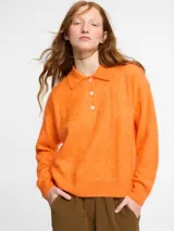 Sweater de punto de cachemira color turquesa con cuello polo y cierre frontal de tres botones. Presenta una textura suave tipo pelo, manga larga y terminaciones acanaladas en puños y ruedo.